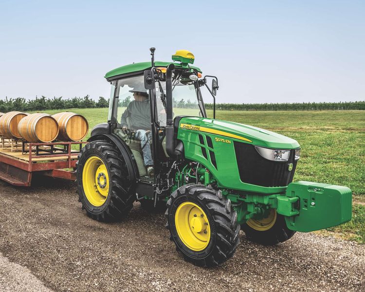 John Deere tractor hauling wooden barrels